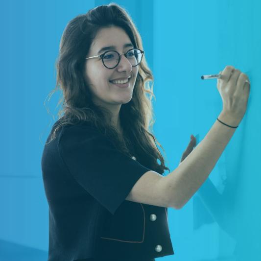 A female Saint-Gobain intern smiles while writing on a board for her corporate internship