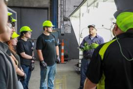 A Saint-Gobain CertainTeed employee speaks with students on the plant floor during SFRC, a workforce development program