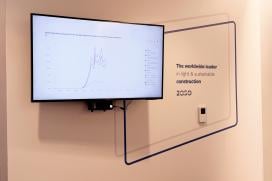 Screen displays current energy usage of the building. A graphic on the wall reads "The worldwide leader of light & sustainable construction."
