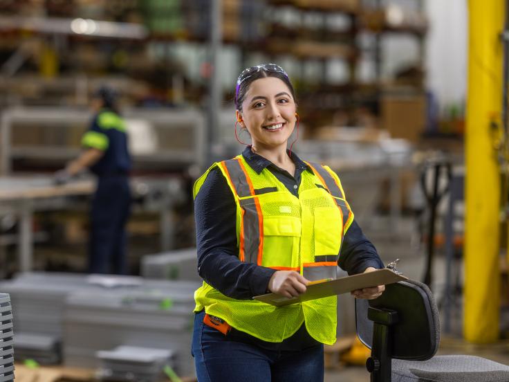 Women wearing a safety vest stands on the warehouse floor