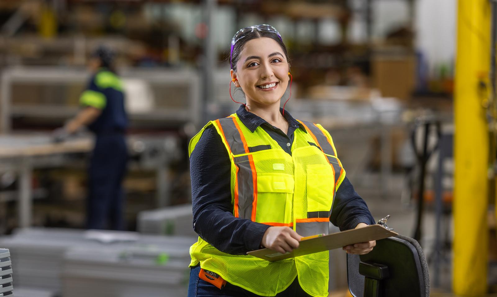 Women wearing a safety vest stands on the warehouse floor