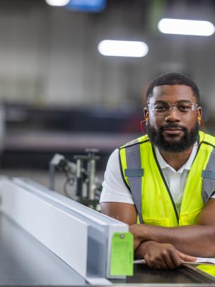 Skilled manufacturing employee inspecting metal products in a modern industrial facility.